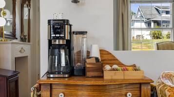 Un aparador de madera con una cafetera, una licuadora y una caja de bolsitas de té.