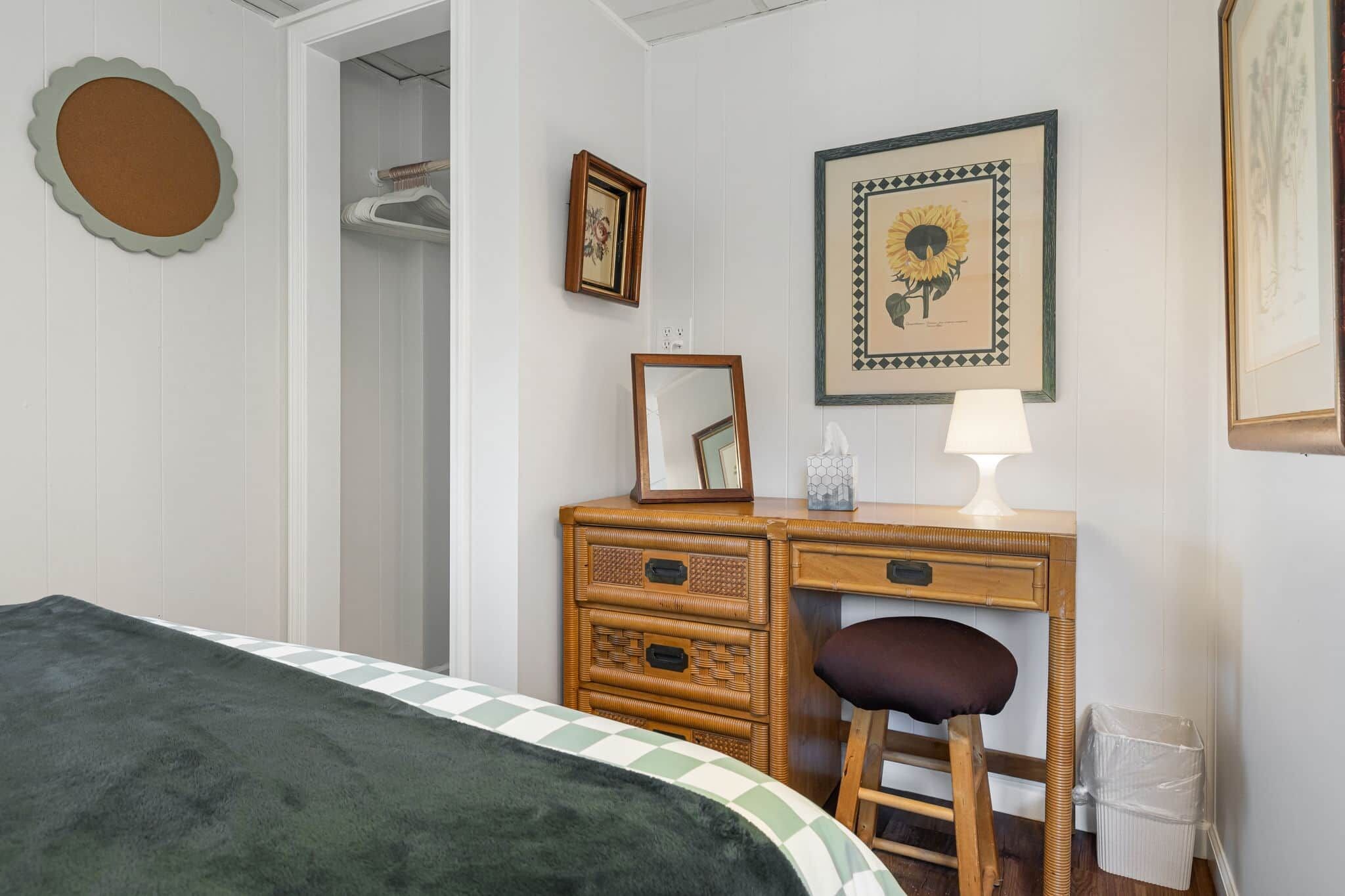 Un dormitorio con una cama, un aparador de madera, una silla, un espejo y dos cuadros en la pared.