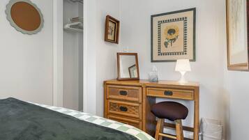 Un dormitorio con una cama, un aparador de madera, una silla, un espejo y dos cuadros en la pared.