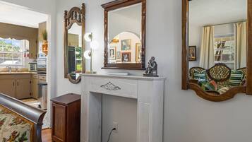 A room with a white dresser, a large mirror, and a sofa with patterned cushions.