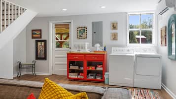 A compact living space with a staircase, a red entertainment unit, a washing machine, and a window with a view.