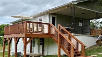 A two-story house with a wooden deck, a staircase, and a covered porch.