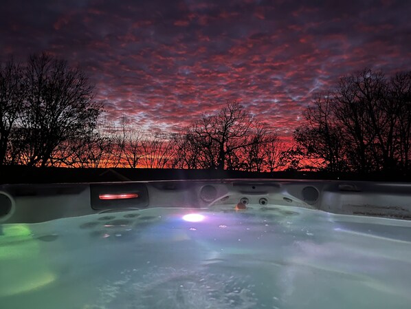A hot tub with a view of a sunset and trees.