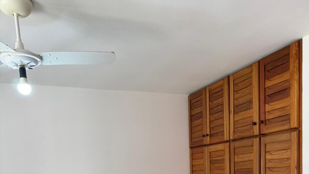 A bedroom with two beds, a ceiling fan, wooden wardrobe, and a towel on the floor. - Nazareth Residential, apartment 16 (Porto Seguro)