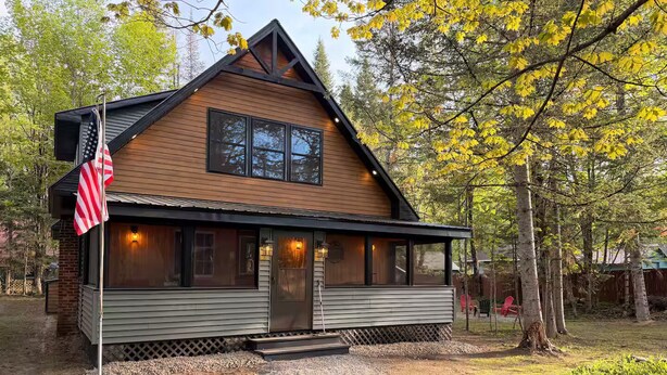 Une cabane avec un porche à l’avant, un drapeau et une façade en bois.