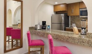 A kitchen with granite countertops, stainless steel appliances, and pink bar stools. - Whale watch from balcony of Cozy 1-bedroom Cabo San Lucas (Cabo San Lucas)