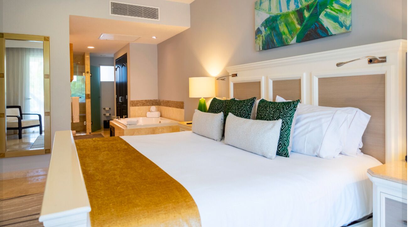 A hotel room with a large bed, a bathtub, a desk, and a chair.