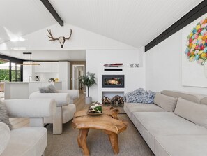 Ein modernes Wohnzimmer mit Kamin, einem aufgehängten Hirschgeweih und einem farbenfrohen Blumenbild.