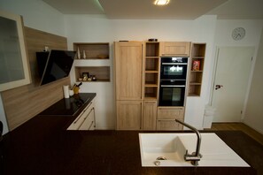 A modern kitchen with a built-in oven, a sink, and wooden cabinetry. - Nikolai Suite (Hamburg)
