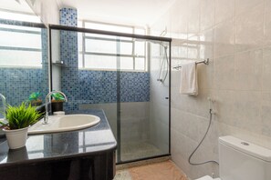 A bathroom with a glass-enclosed shower, a sink, and a toilet. - Shopping at your doorstep | 3-Bedroom Apartment in Barra (Salvador)