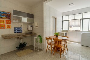 A kitchen with a dining area, a sink, a window, and a refrigerator. - Shopping at your doorstep | 3-Bedroom Apartment in Barra (Salvador)
