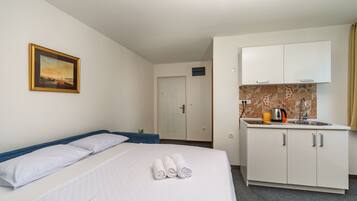 Une chambre d’hôtel avec un lit, un tableau encadré, une kitchenette et une porte.