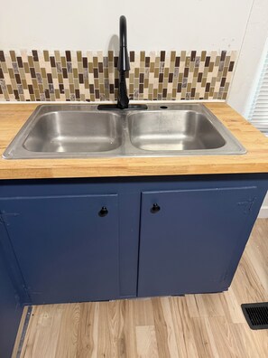 Eine Küche mit doppeltem Spülbecken, einer Holz Arbeitsplatte und blauen Schränken.