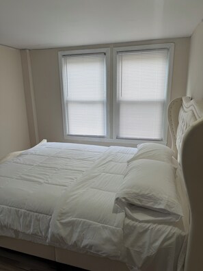 A bedroom with a bed, two windows with blinds, and a headboard. - Charming 3-bedroom apartment with AC in Naples (Naples)