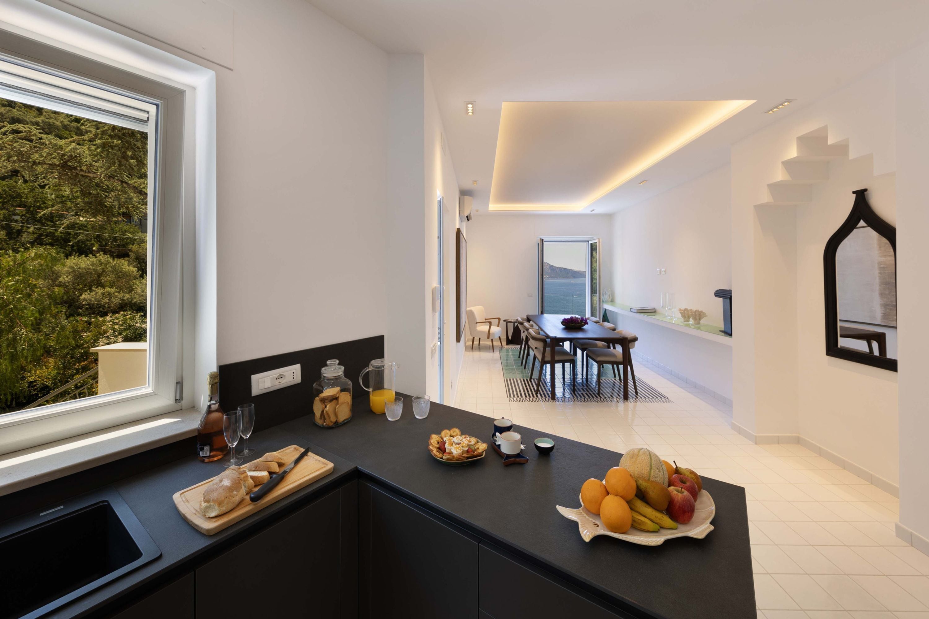 Cozinha moderna com vista para o exterior, área de jantar e escada para outro andar.