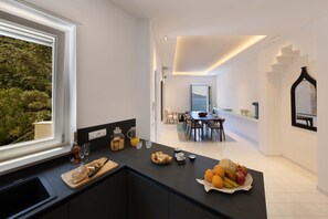 A modern kitchen with a view of the outdoors, a dining area, and a staircase leading to another level. - Villa Gisolfi in Massa Lubrense (Massa Lubrense)