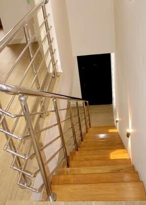 Eine Treppe mit Metallgeländern und Holzboden, die zu einem dunklen Raum führt.