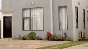 A modern two-story building with large windows, a flat roof, and a paved entrance area. - Peaceful 3-bedroom building with AC in vibrant Accra (Accra)
