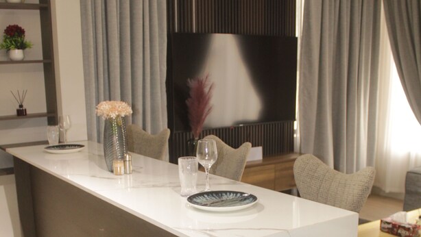 A modern kitchen with a marble countertop, a built-in TV, and a seating area with a sofa and a coffee table. - Peaceful 3-bedroom building with AC in vibrant Accra (Accra)