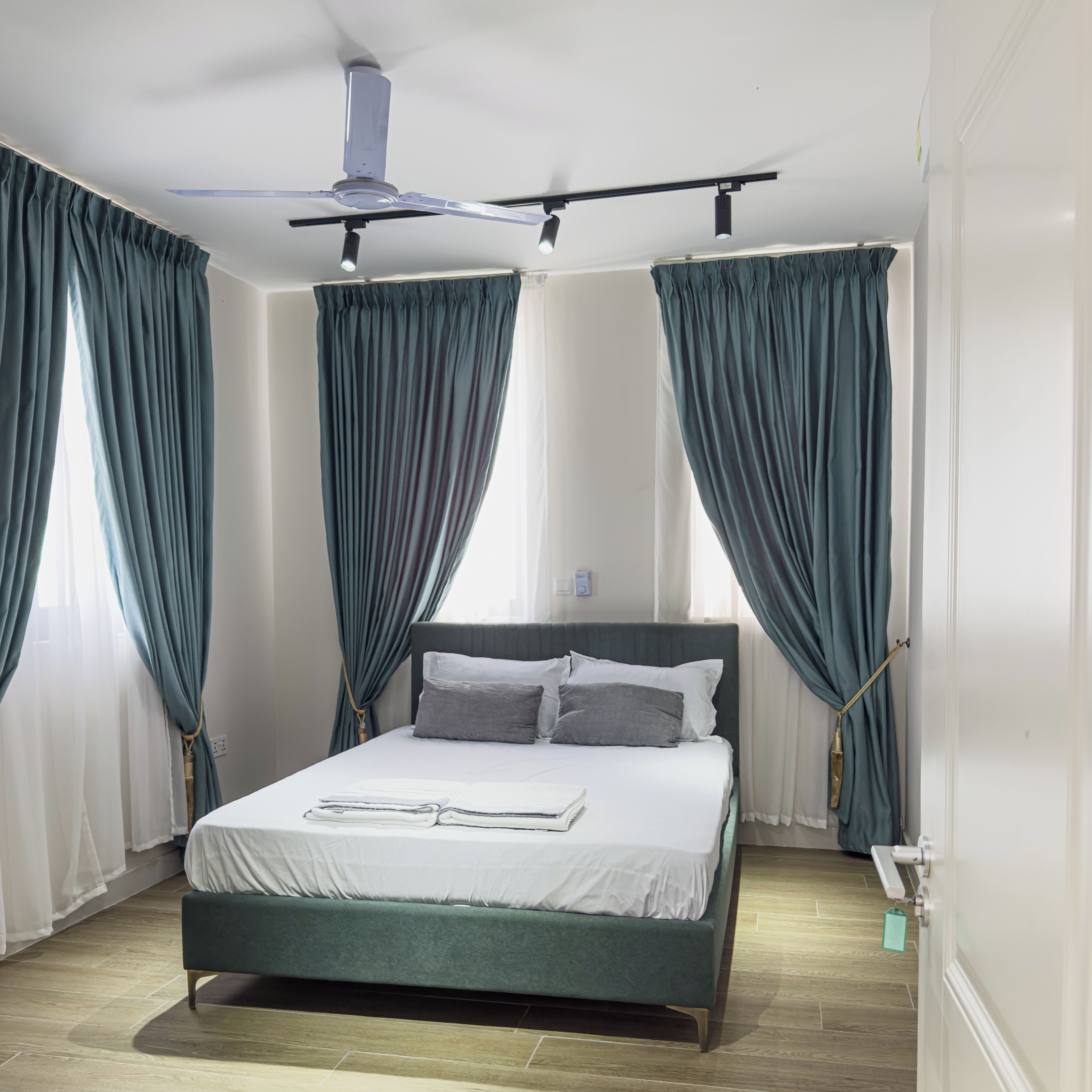 Ein Hotelzimmer mit Bett, Vorhängen, Deckenventilator und Nachttisch.