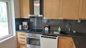 Une cuisine moderne dotée d’appareils électroménagers en acier inoxydable, de meubles en bois, d’un four encastré et d’un lave-vaisselle.