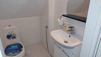 A bathroom with a toilet, a shower, a sink, and a mirror.