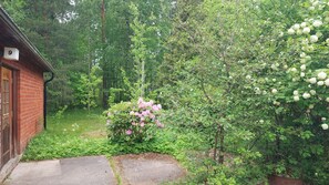 A brick building with a number '9' sign, surrounded by lush greenery and flowering bushes. - Mirage House in Karhumäki (Etelä-Karjala)