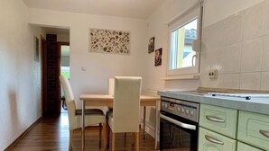 Une cuisine avec un plancher en bois, une table à manger avec des chaises, un four encastré et une fenêtre.