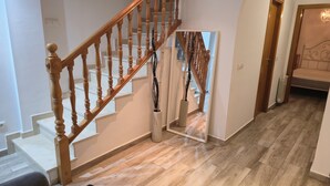 A wooden staircase with a mirror reflecting the stairs, a radiator, and a bed in the adjacent room. - Large Duplex Penthouse with terrace, AC, Wifi and very spacious beds (Orpesa)