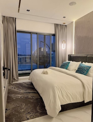 Ein modernes Hotelzimmer mit einem großen Bett, Blick auf die Stadt und einem Balkon mit einer Hängematte.