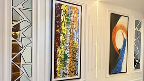 Un passadís amb quadres abstractes, disseny geomètric a la paret i un sòl de marbre.