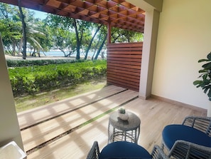 Un espace extérieur abrité, doté d’un plancher en bois, d’une petite table ronde et de meubles en osier.
