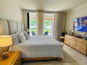Ein Hotelzimmer mit Bett, Fernseher, einem Holzschrank und Blick ins Freie.