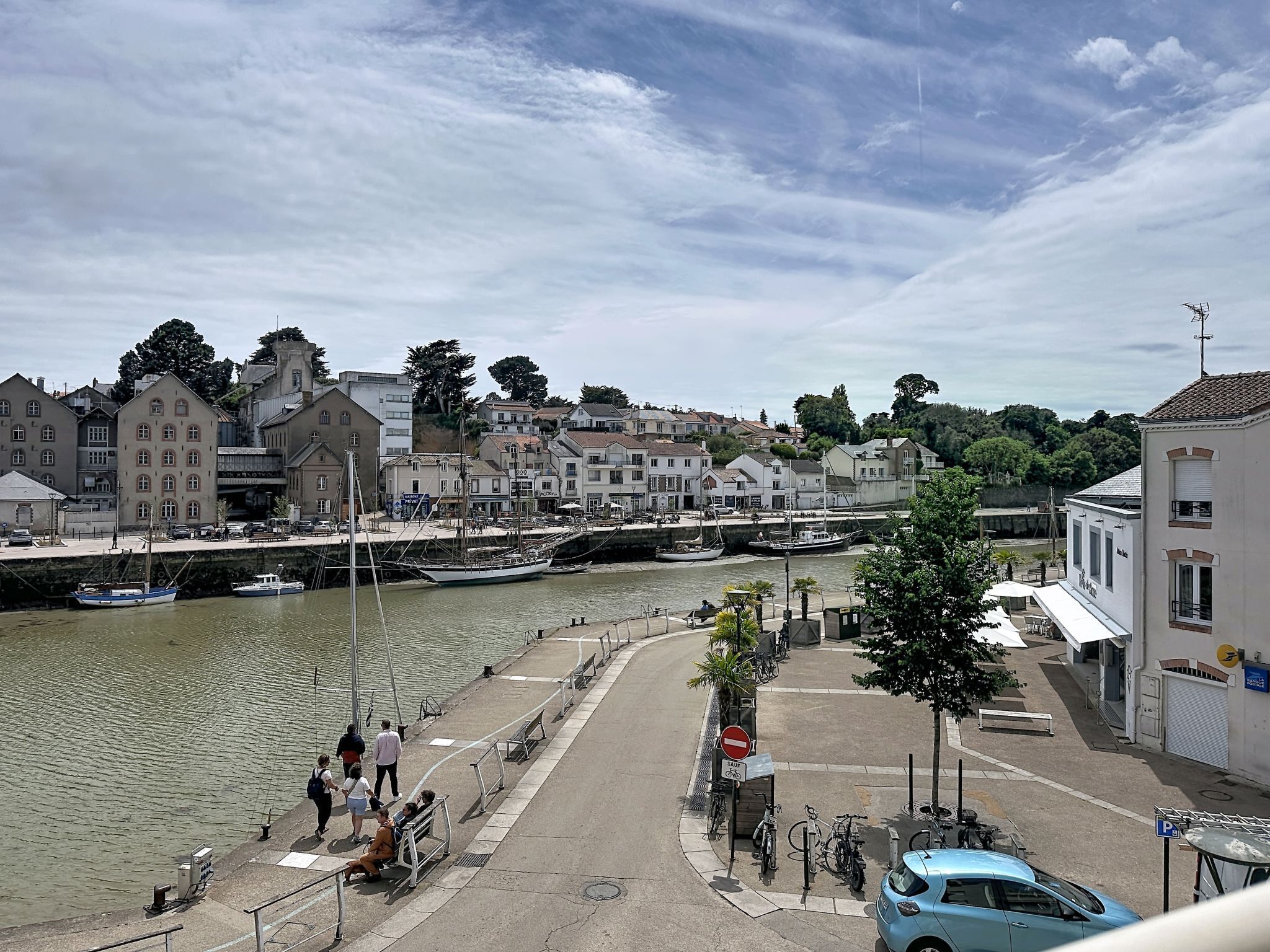 Une vue sur le front de mer, avec des bâtiments, un quai où sont amarrés des bateaux et une promenade piétonne.