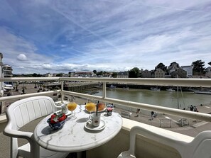 Ein Balkon mit Frühstückstisch, mit Blick auf einen Fluss, auf dem Boote fahren und Gebäude stehen.