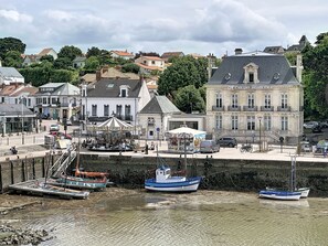 Una zona sul lungomare con barche ormeggiate, un caffè e palazzi con balconi.