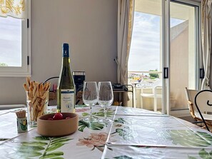 Ett matbord med en vinflaska, glas, en skål med snacks och en blommig duk.