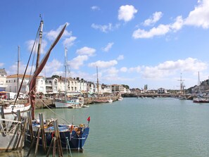 Ein Hafen mit vertäuten Booten, Gebäuden an der Uferpromenade und einem klaren Himmel.