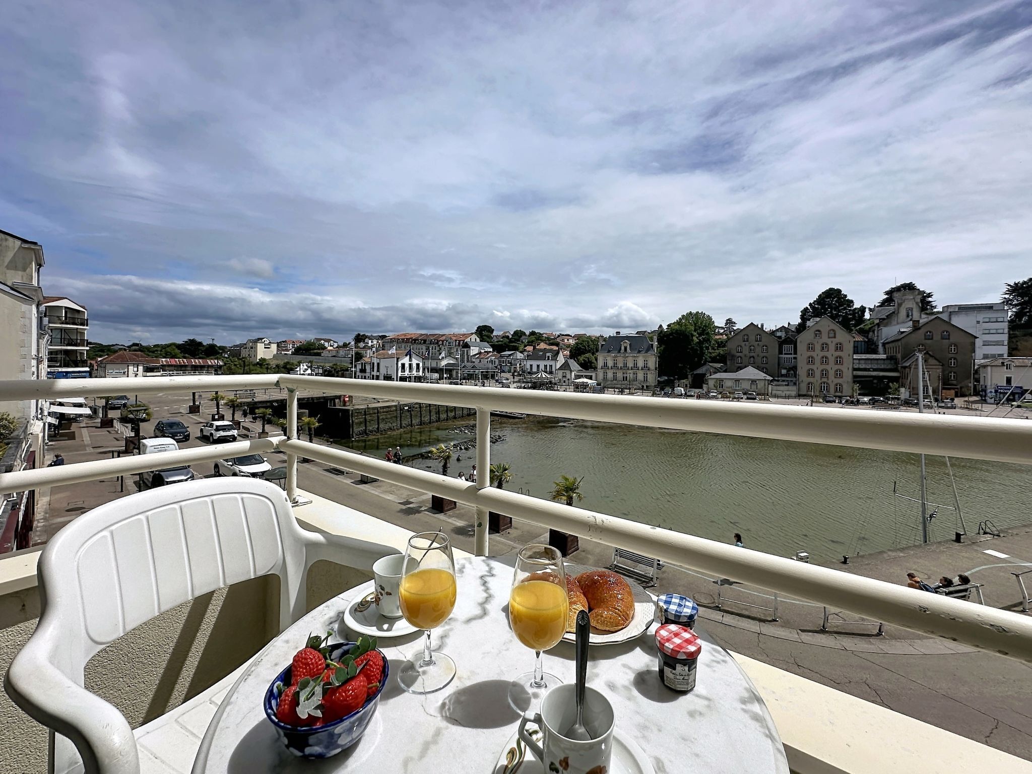Un balcon avec une table préparée pour le petit-déjeuner, d’où l’on peut admirer une rivière et le paysage urbain.