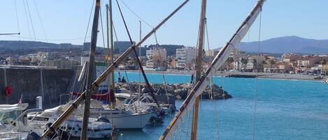 A marina with boats docked, a clear blue sky, and buildings in the background.