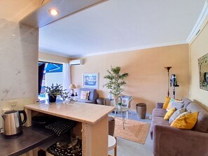 A modern living room with a sofa, a coffee table, a lamp, and a potted plant. - Le Grand Large by Interhome (Cagnes-sur-Mer)
