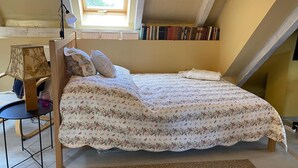 Et soveværelse med seng, skrivebord, lampe og et vindue.