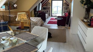 An attic bedroom with a glass ceiling, a dining area with a glass table, and a cozy reading nook.