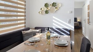 Un coin repas avec une table dressée pour quatre personnes, un canapé et un élément décoratif mural.