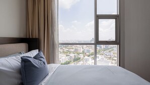 Une chambre d’hôtel avec un lit, une fenêtre donnant sur la ville et des rideaux.