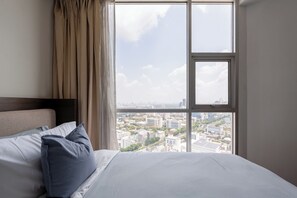 Ein Hotelzimmer mit Bett, Fenster mit Stadtblick und Vorhängen.