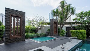 Un espace piscine aménagé sur le toit, avec une terrasse en bois, une petite piscine et de la verdure tout autour.