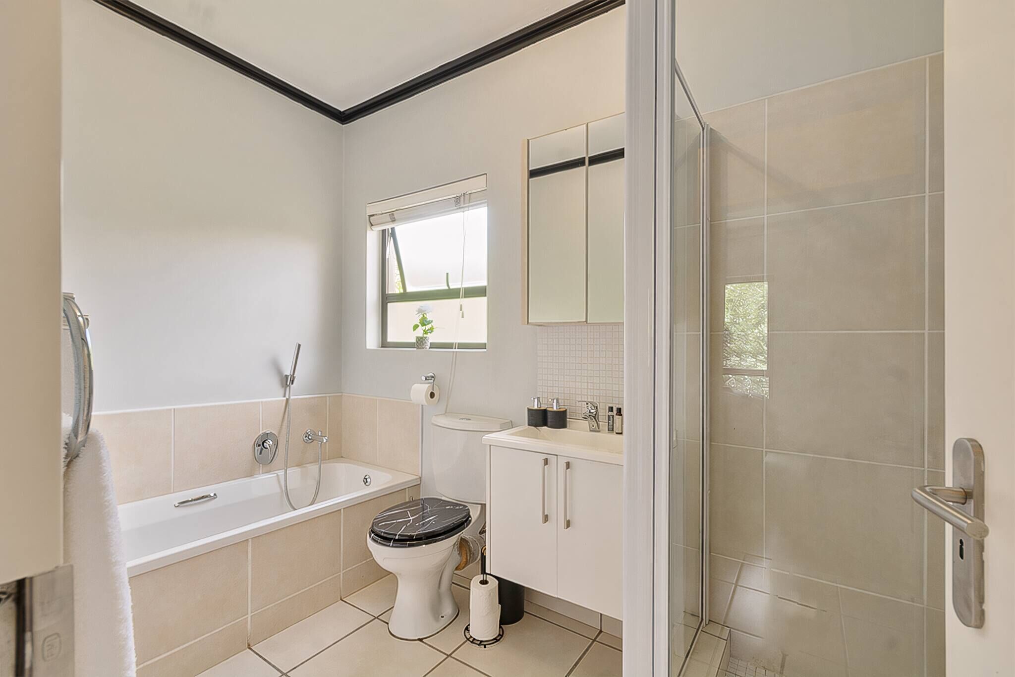 A bathroom with a bathtub, toilet, sink, and a shower area.