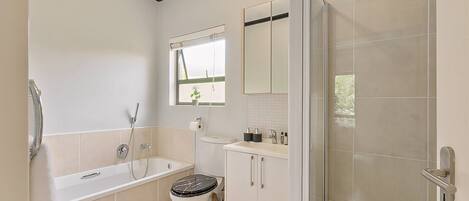 A bathroom with a bathtub, toilet, sink, and a shower area.