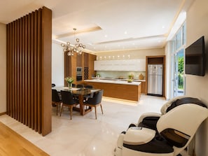 A modern kitchen with a central island, a dining area with a glass table, and a seating area with chairs. - Royal Riverside Villa near Kazbegi with Pool & Mountain Views (Tsitelsopeli)